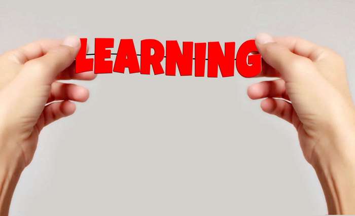 Hands holding red letters spelling LEARNING
