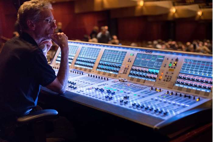 Man operating a sound mixing board at a concert