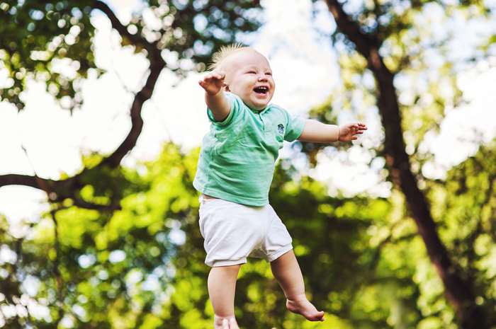 Happy baby boy laughing outdoors in a park