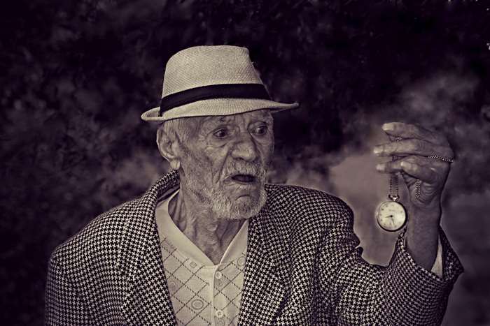 Elderly man in hat holding a pocket watch