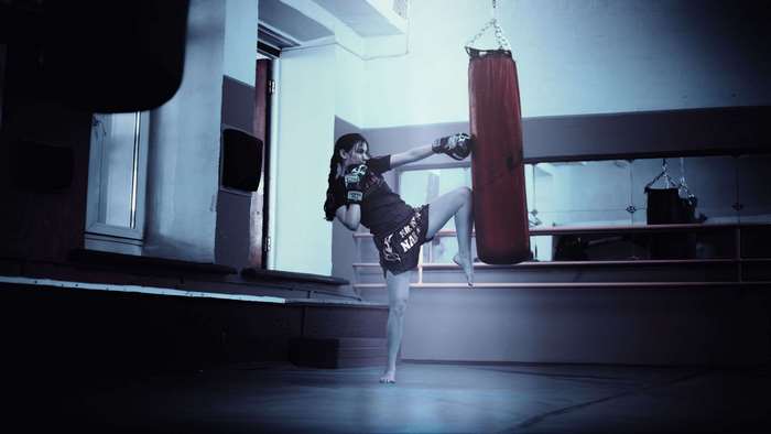 Woman kicking a punching bag in a gym