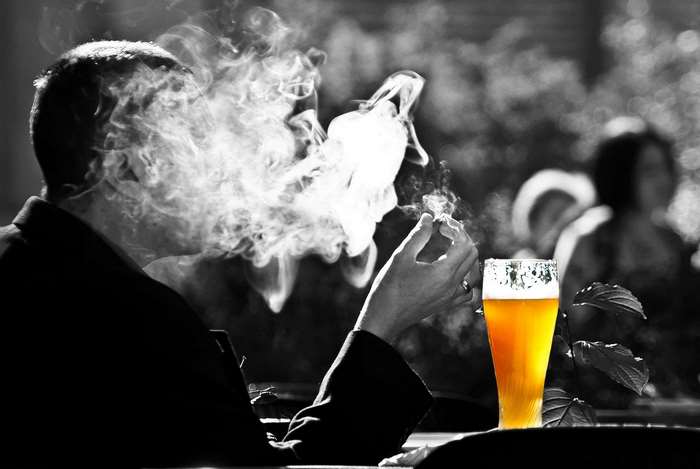 Man smoking cigarette with beer