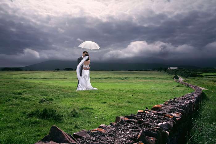 Bride and groom under umbrella in Irish landscape 4K