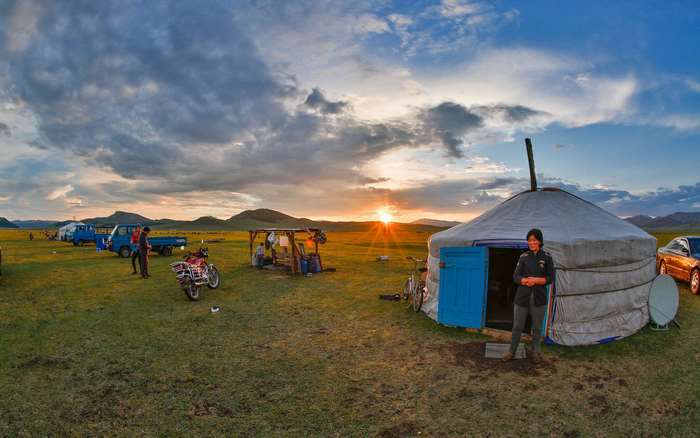 Mongolian Ger camp at sunset with vehicles and people