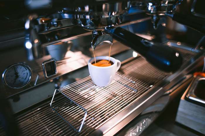 Espresso being brewed into a white cup from a stainless steel machine