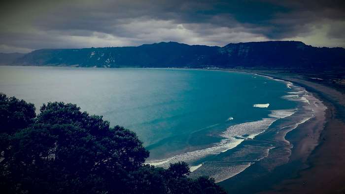 Stormy Coastline with Turquoise Ocean and Dark Mountains