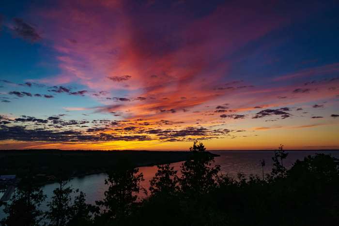 Sunset over a bay with colorful clouds and trees