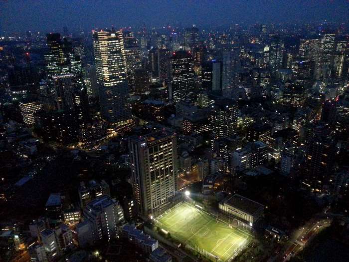 Night view of Tokyo cityscape with illuminated buildings and soccer field