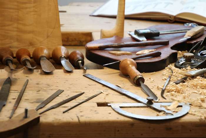 Woodworking tools and violin parts on a workbench