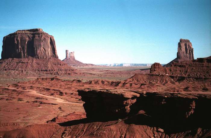 Monument Valley landscape with red rock formations under a blue sky