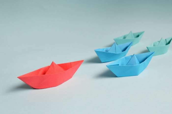 Origami paper boats in different colors on a blue background