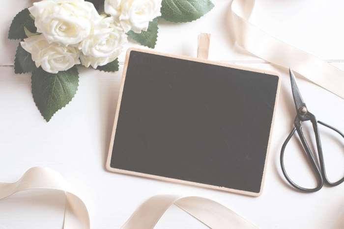 White roses, chalkboard, and scissors on a white surface