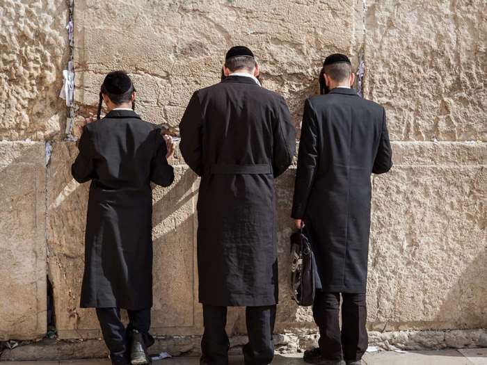 Three Jewish men praying at the Western Wall in Jerusalem