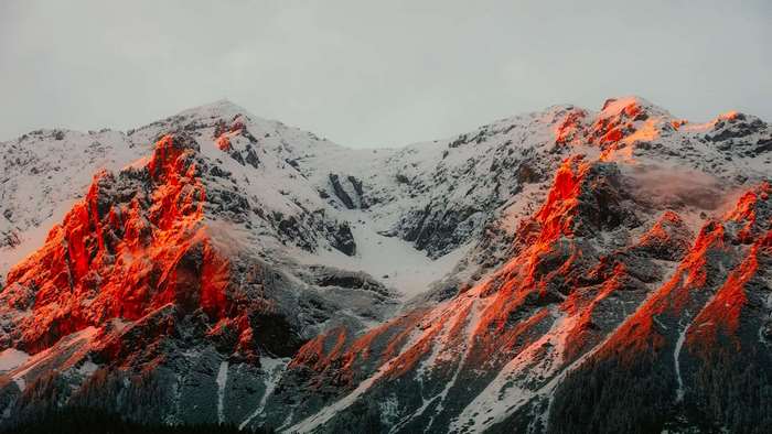 Snowy mountains illuminated by orange sunset light