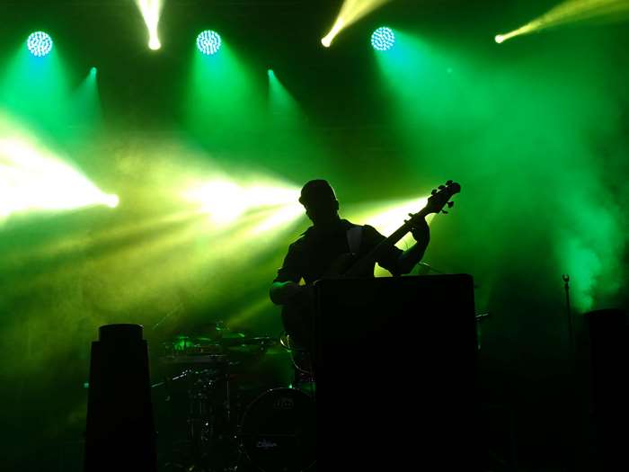 Silhouette of a guitarist performing on a stage with green lights