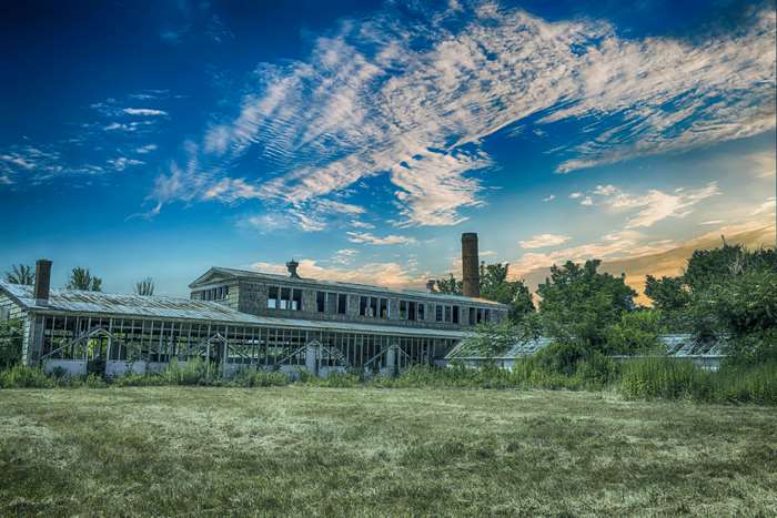 Abandoned industrial building with smokestack under blue sky