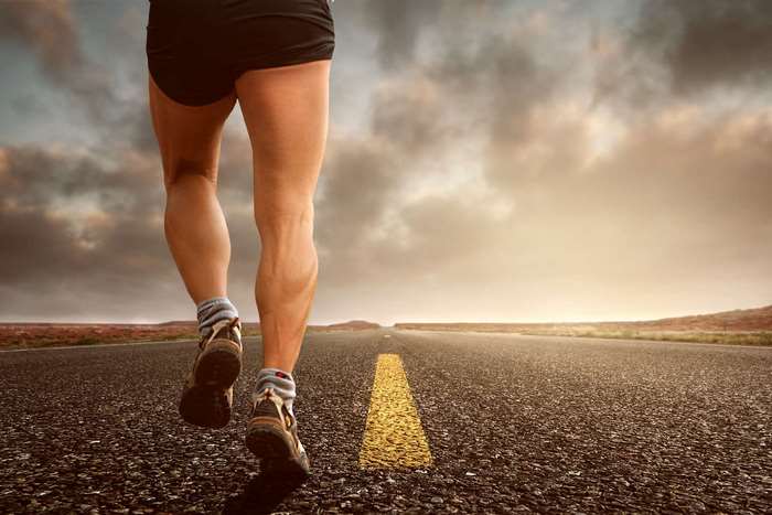 Runner's legs on a road with cloudy sky