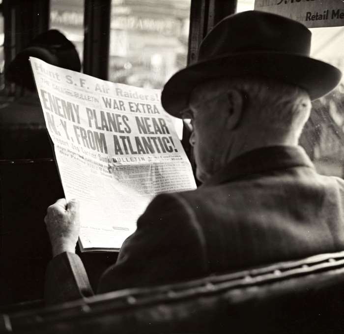 Man reading newspaper about enemy planes near NY from Atlantic
