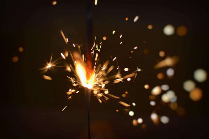 Sparkler with sparks and bokeh in dark