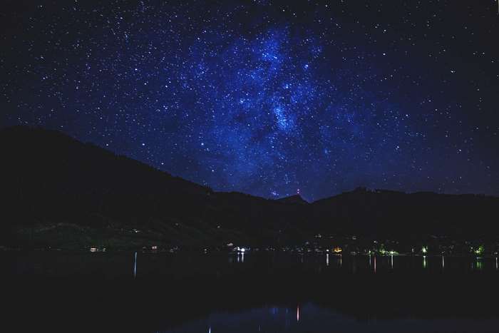 Starry night sky over a lake and mountains