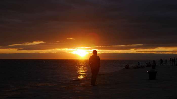 Sunset over the ocean with a person on the beach