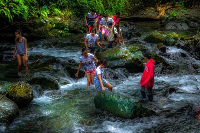 Group of people crossing a rocky stream