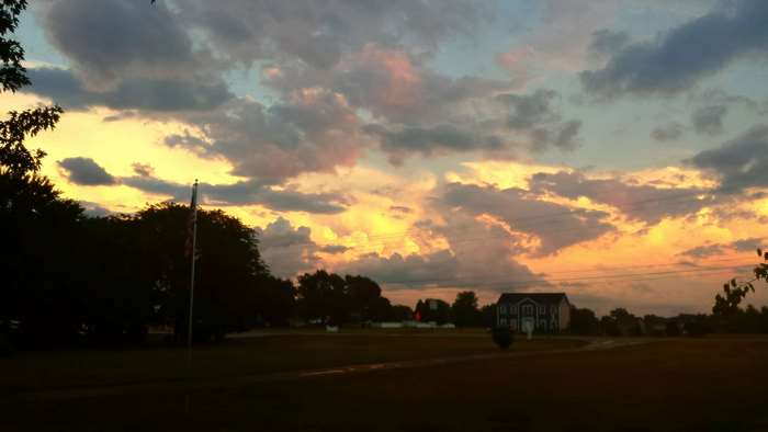 Sunset clouds over a rural landscape with a house