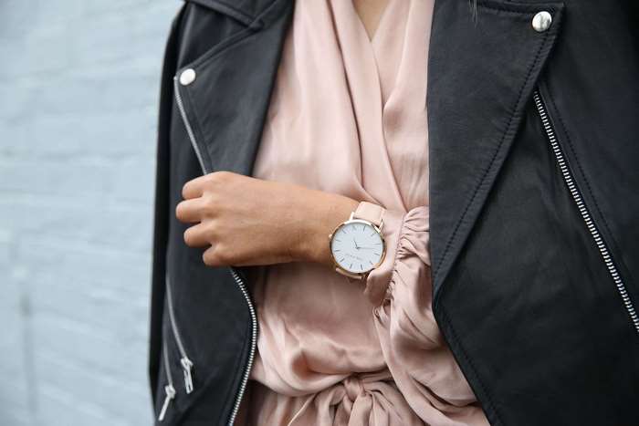 Woman wearing a black leather jacket and pink dress with a watch