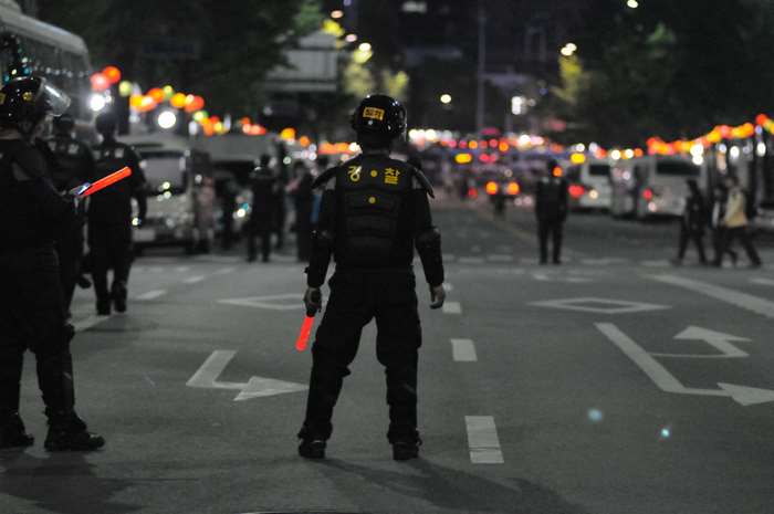 Police officers with riot gear and batons on a city street at night