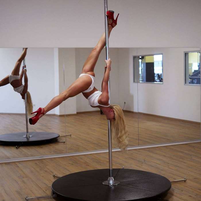 Woman performing pole dance in white polewear