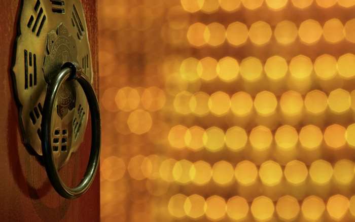 Close-up of a golden door knocker with bokeh lights