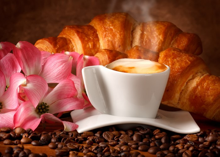 Coffee cup with croissants and pink dogwood flowers