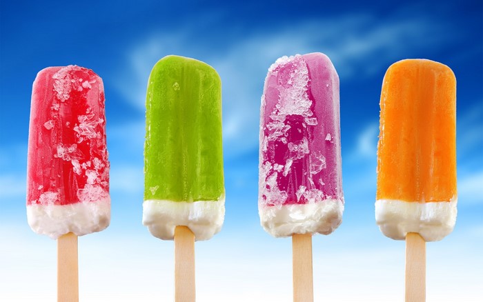 Four colorful popsicles on sticks against a blue sky