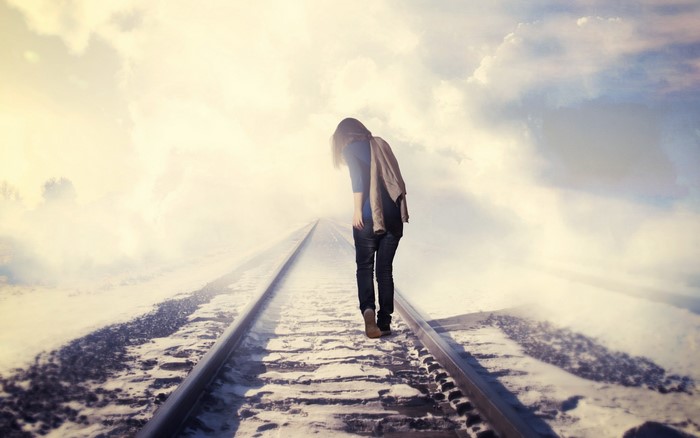 Girl walking on snowy railway tracks