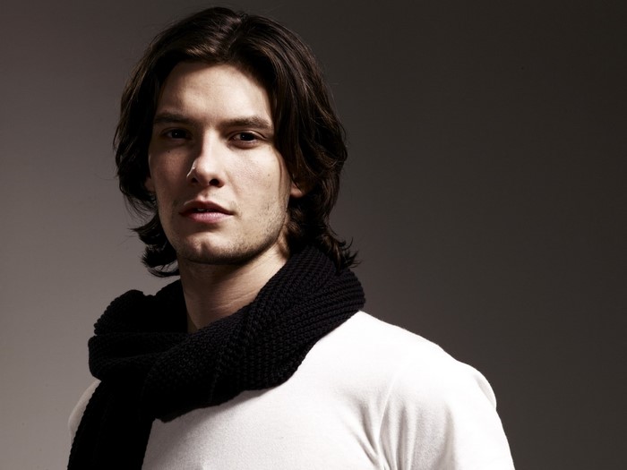 Man with long dark hair wearing a black scarf