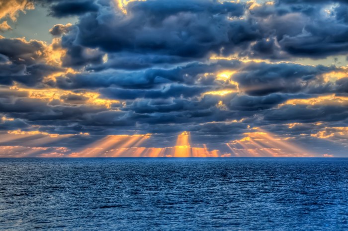 Sun Rays Shining Through Clouds Over the Sea