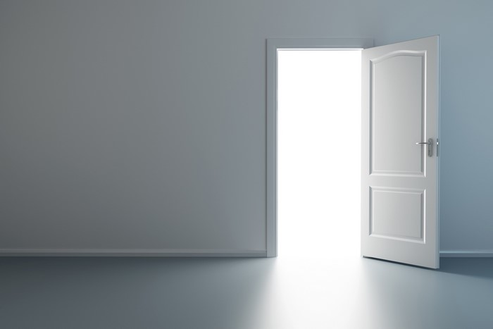 Minimalist interior with an open white door and bright light
