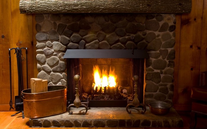 Stone fireplace with a roaring fire and copper bucket