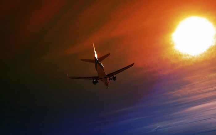 Airplane flying towards the sun at dusk