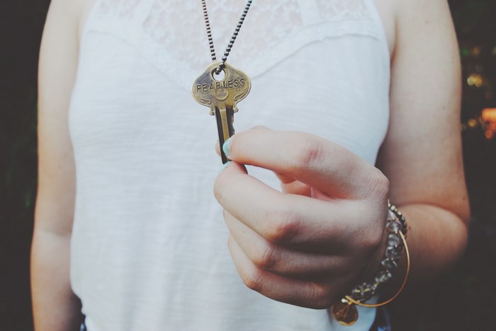 Woman holding a vintage 'Fearless' key necklace
