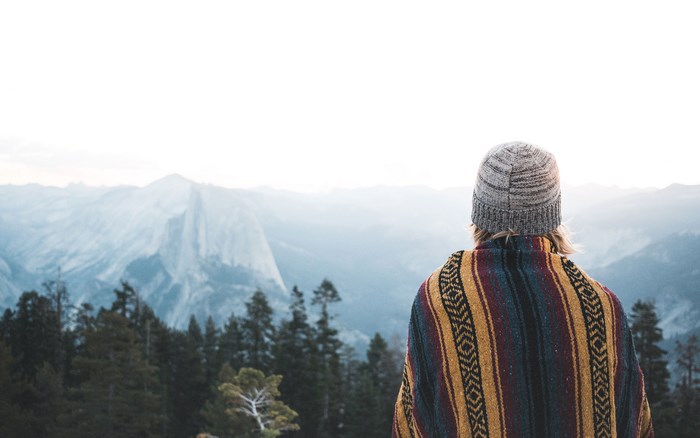 Person in beanie and poncho overlooking mountains
