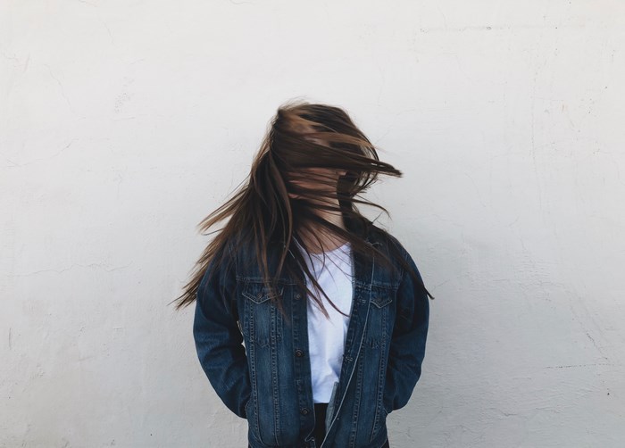 Woman with hair in face wearing denim jacket