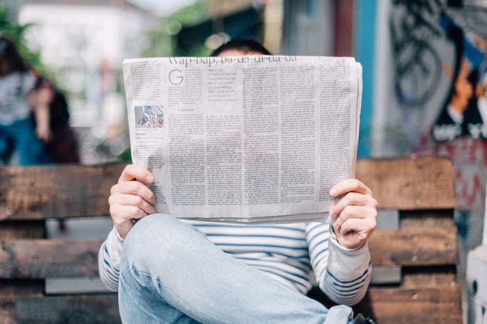 Person reading a newspaper outdoors
