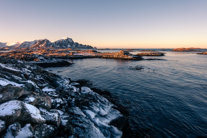 Snowy mountains and rocky coast at sunrise in Vesteralen, Norway