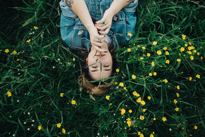 Woman in denim lying in a field of grass and flowers