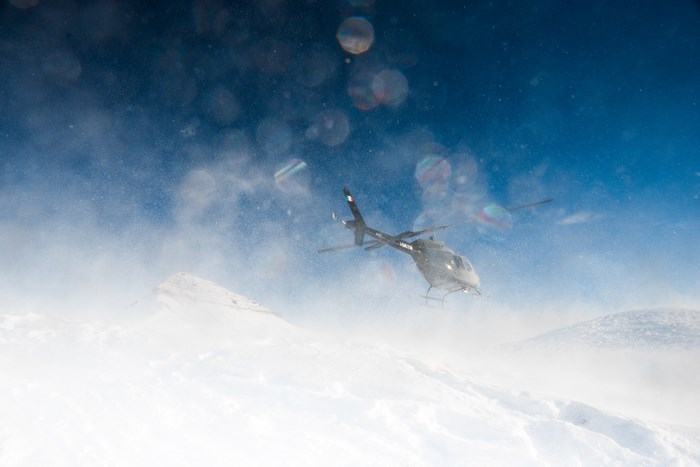 Helicopter flying over snowy mountains in windy conditions