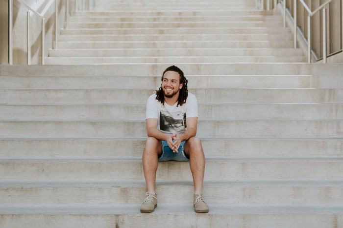 Man with dreadlocks sitting on concrete stairs