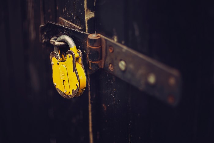 Yellow padlock on a dark wooden door