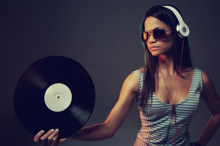 Woman with headphones and sunglasses holding a vinyl record