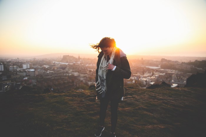 Woman on a hilltop overlooking a cityscape at sunset
